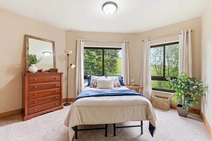 Room featuring light-colored carpet flooring, light beige wall paint, and natural wood baseboards