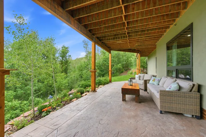 Spacious covered patio featuring a stamped concrete surface, exposed wood beam ceiling, and timber support columns