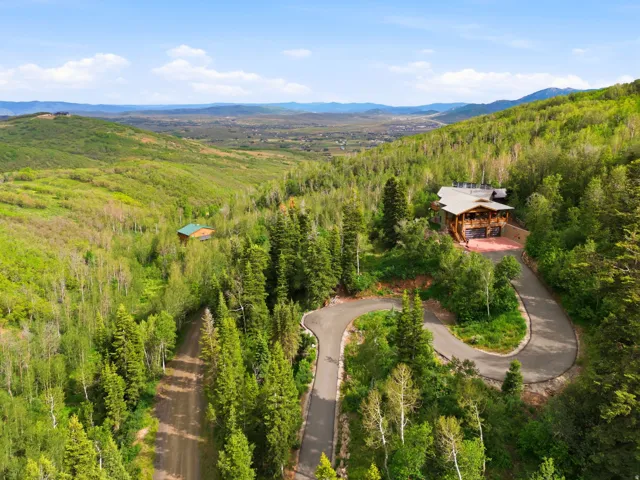 Wood-sided residence with multiple decks, an attached garage, and a paved driveway