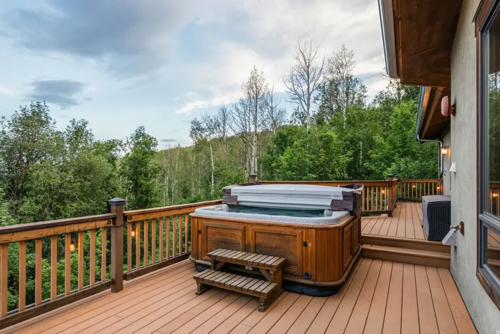 Expansive outdoor deck featuring a built-in hot tub with wood-finish steps
