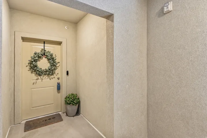 Recessed entryway featuring a paneled door, light-toned walls, and a visible digital door lock