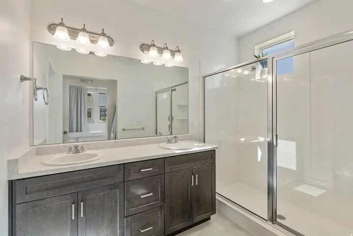 Double vanity with dual undermount sinks, stone-finish countertop, and dark wood-finish cabinetry