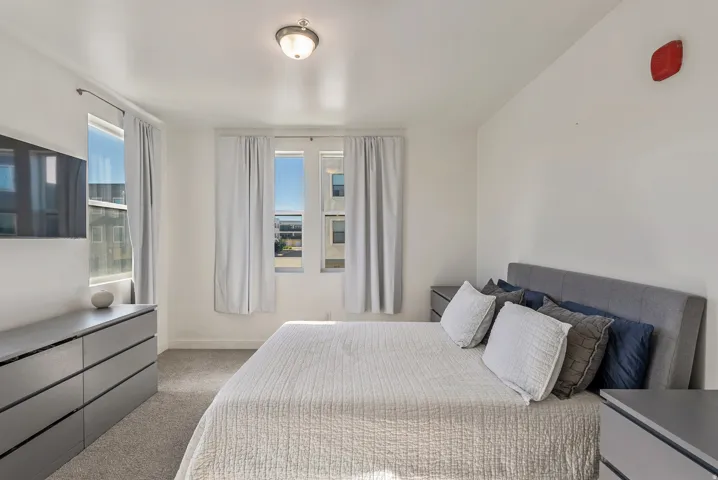 Bright room featuring multiple windows with white curtains, recessed lighting, and soft grey carpeting