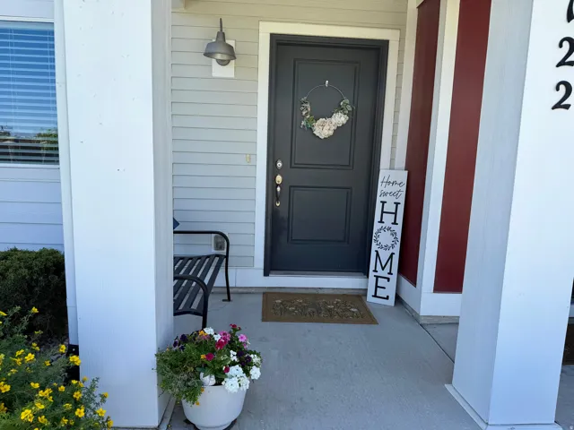 Inviting entry featuring a paneled front door, exterior sconce lighting, and a concrete porch