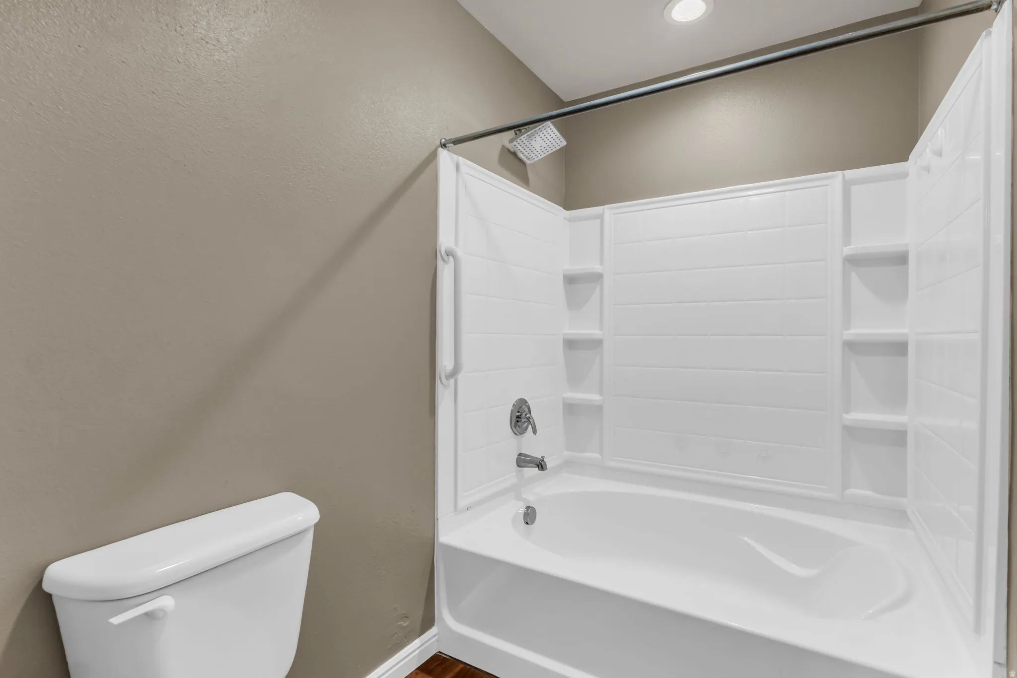 Primary bath featuring a white tub-shower combination with integrated shelving, chrome fixtures, and a rain shower head.