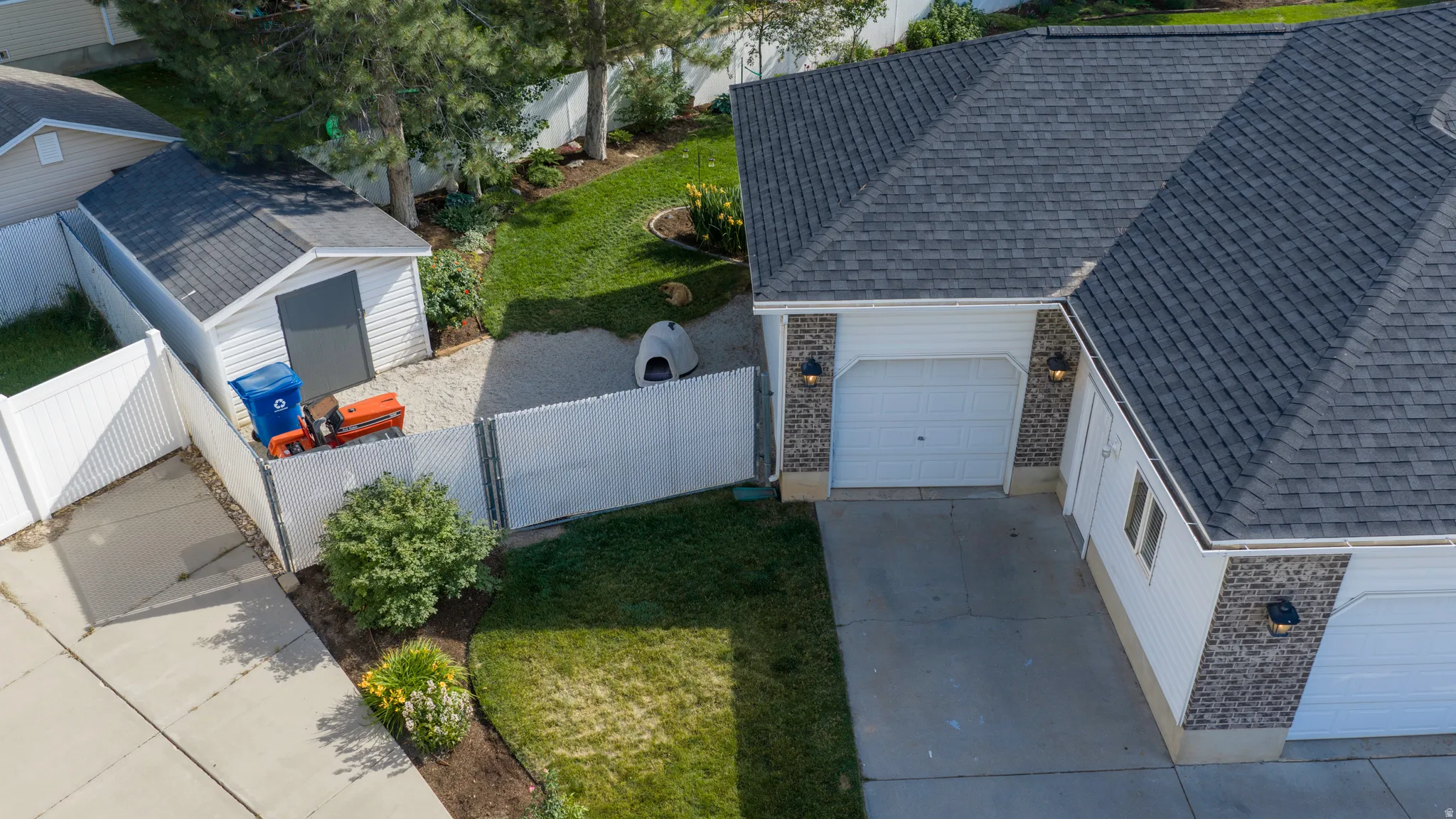 Side yard featuring a white shed, gravel ground cover, and a white fence