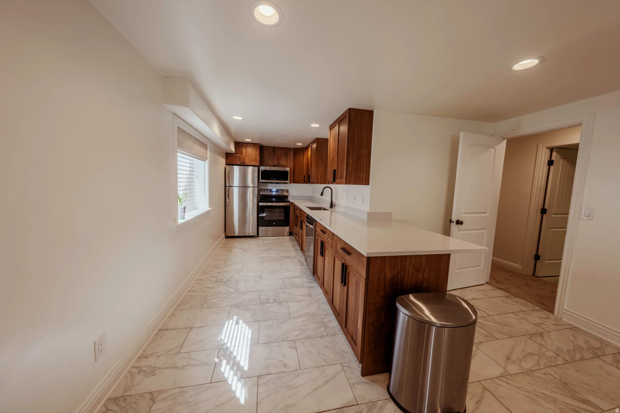 Kitchen featuring wood-finish cabinetry, white countertops, and stainless steel appliances
