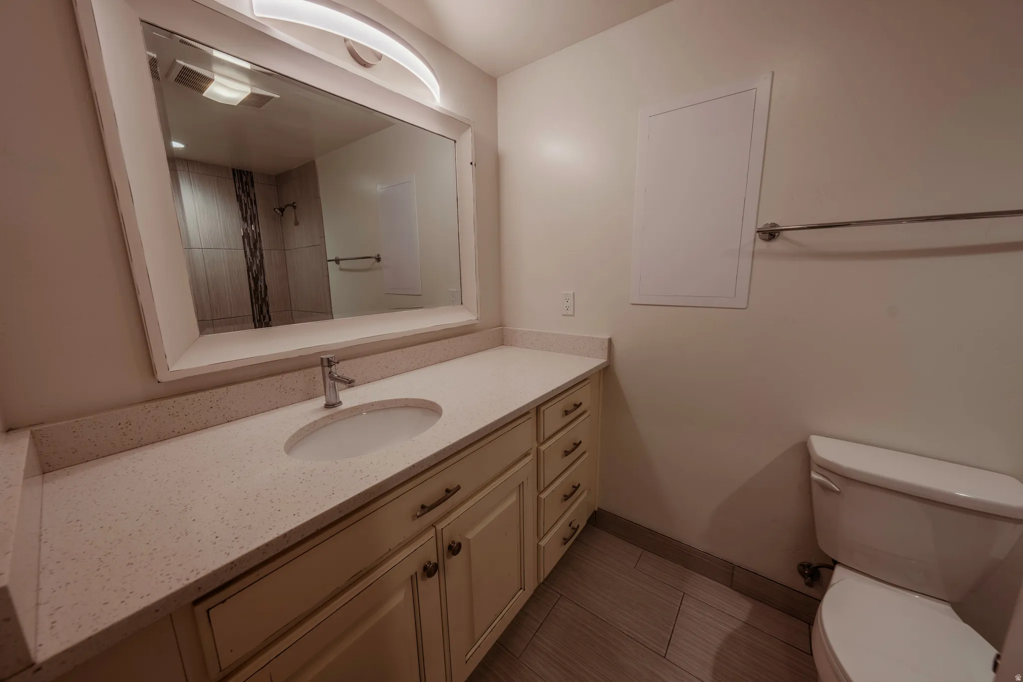 Bathroom vanity featuring a light-toned countertop, undermount sink with a chrome faucet, and ample storage cabinetry