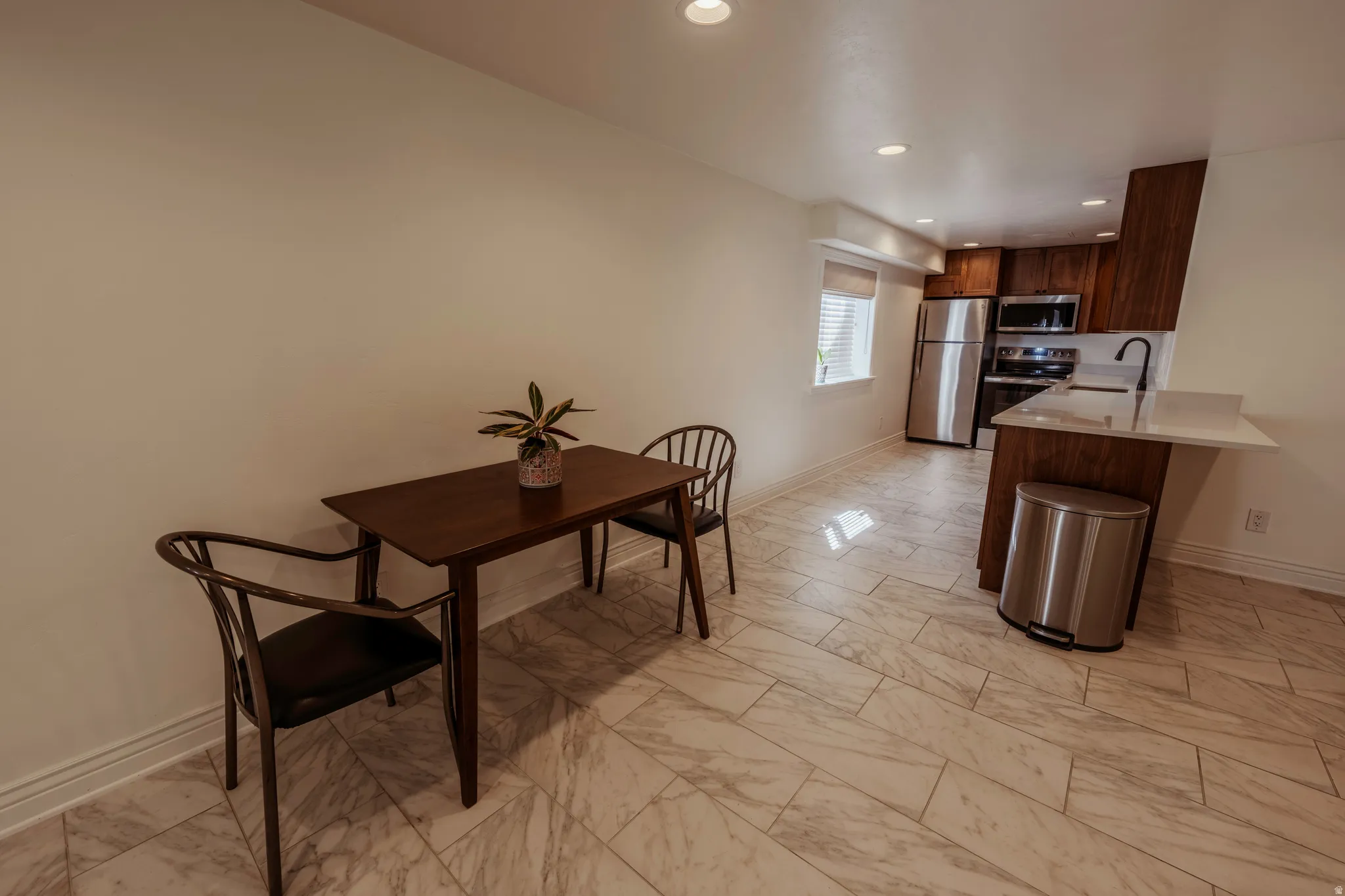 Open-concept living area featuring large format floor tiles and recessed lighting