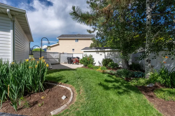Expansive backyard featuring a lush lawn, mature trees, and established garden beds with decorative curbing