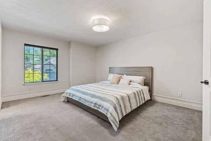 Spacious room featuring neutral carpeting, white painted walls, and a recessed window with dark blinds