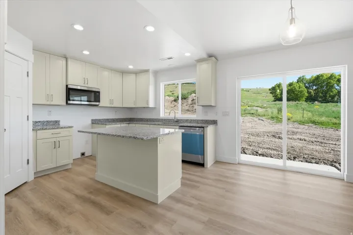 Spacious kitchen with wood-finish flooring, light-toned cabinetry, and granite countertops