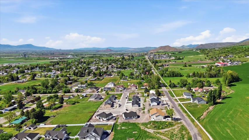 Rural community setting with expansive green fields, mature trees, and distant mountain ranges