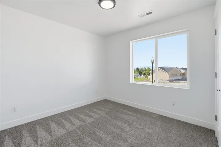Neutral color palette featuring a large window, recessed lighting, white trim, and patterned carpet