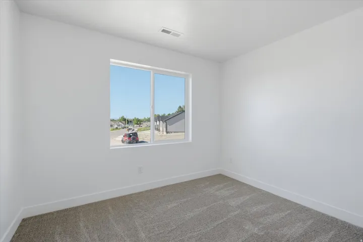 Bright room featuring a large window, neutral carpeting, white walls, and white trim
