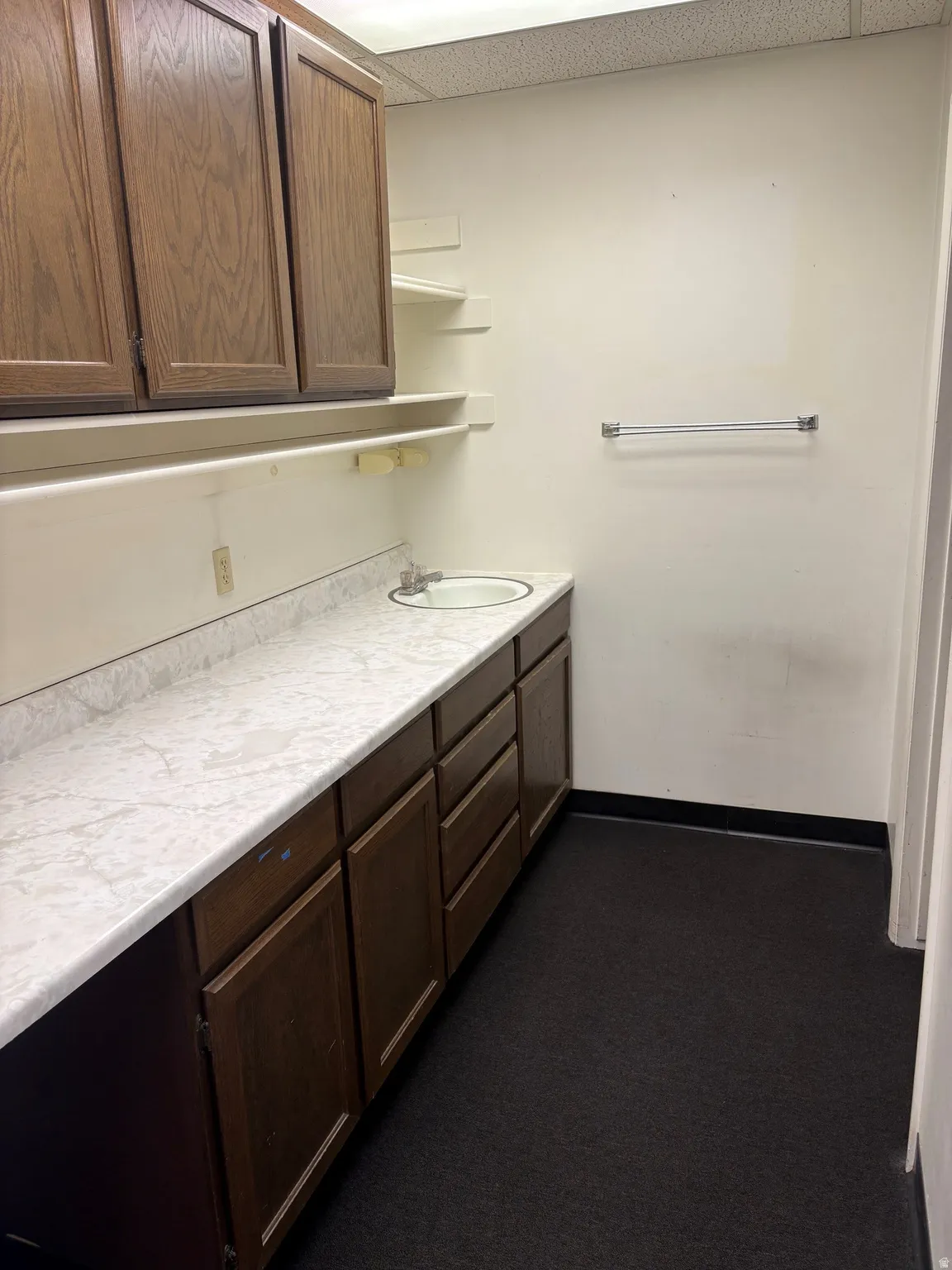 Vanity area featuring an integrated sink, dark wood-finish cabinetry, and a white marble-patterned countertop