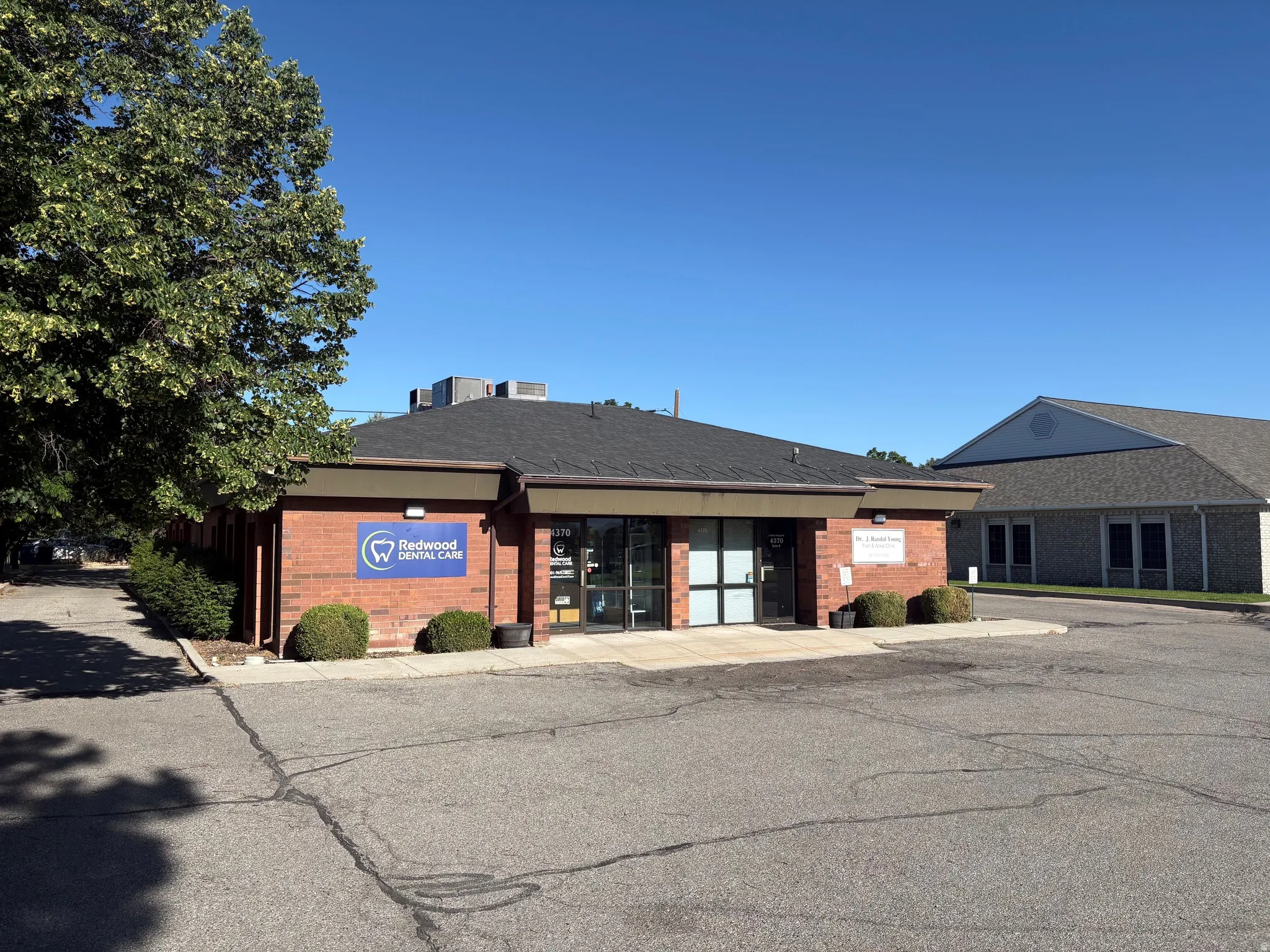 Commercial brick building with a dark shingle roof and a prominent entrance
