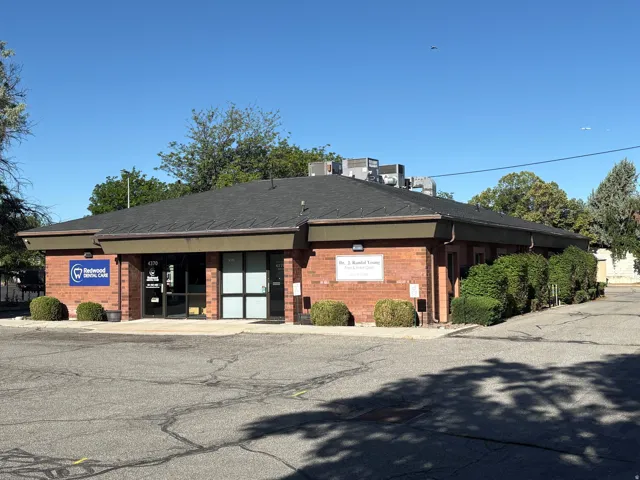 Commercial brick building featuring a dark shingle roof and multiple large windows