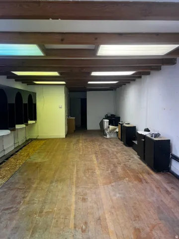Spacious interior featuring exposed wooden beams and recessed panel lighting