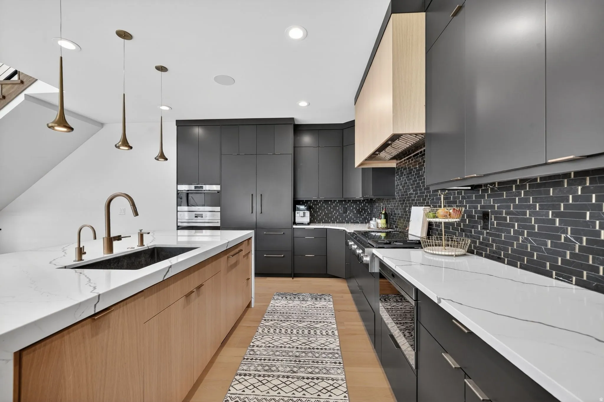Modern kitchen featuring a large island with a composite sink and bronze-finish fixtures