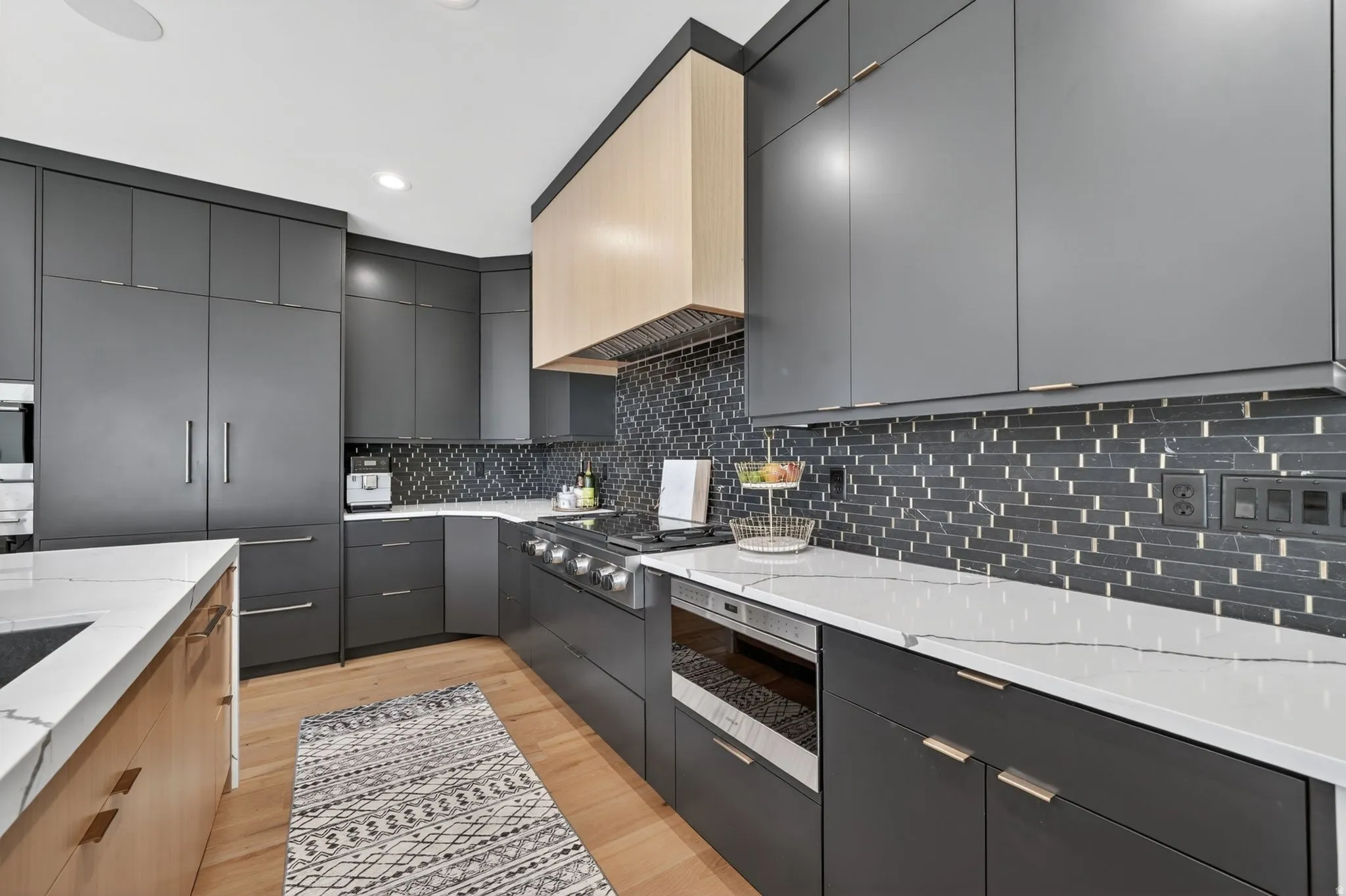 Modern kitchen featuring flat-panel cabinetry, white stone countertops, and a full-height tile backsplash