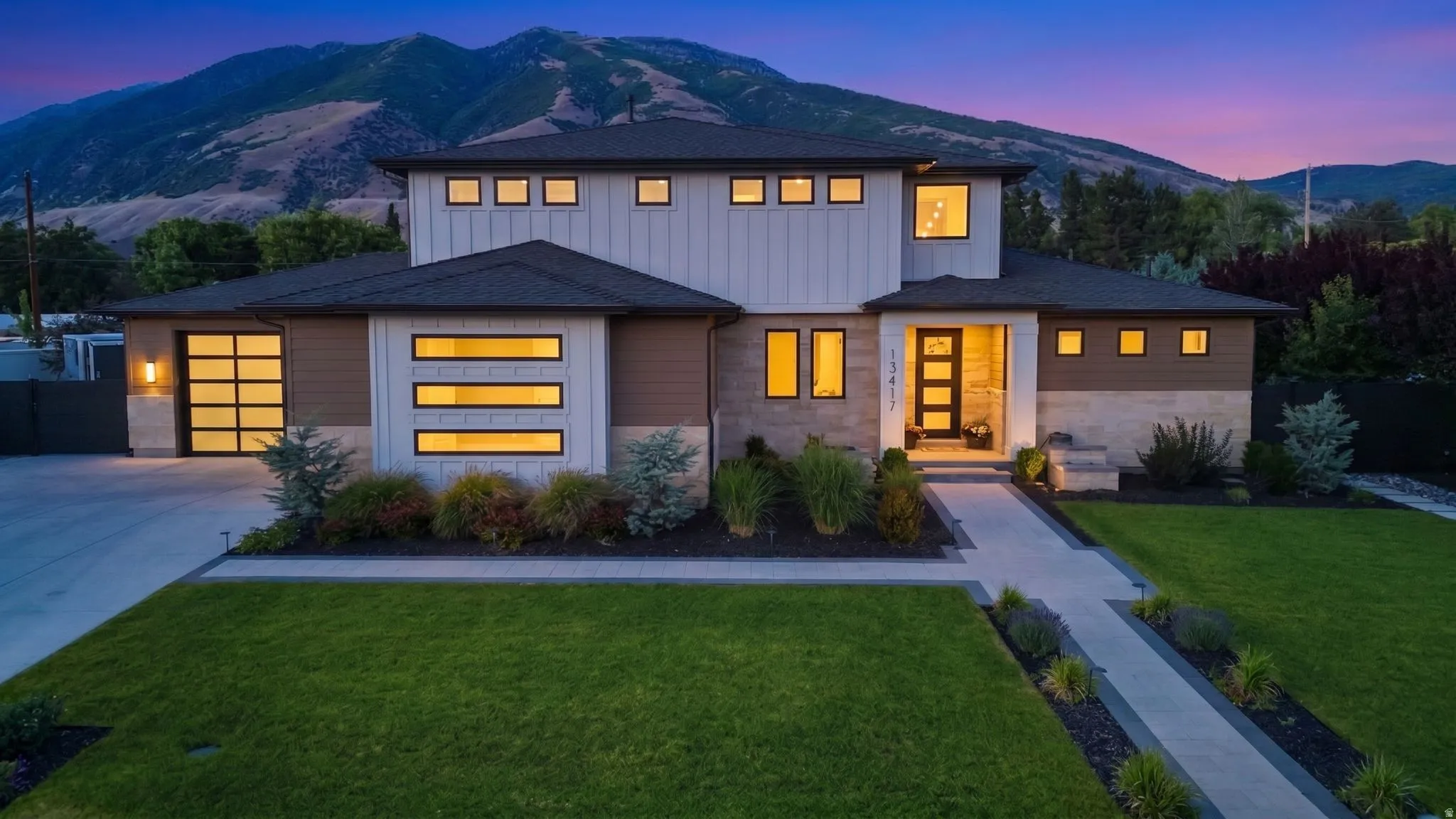 Modern architectural residence featuring a prominent glass-paneled garage door, a patterned entry door, and a stone facade