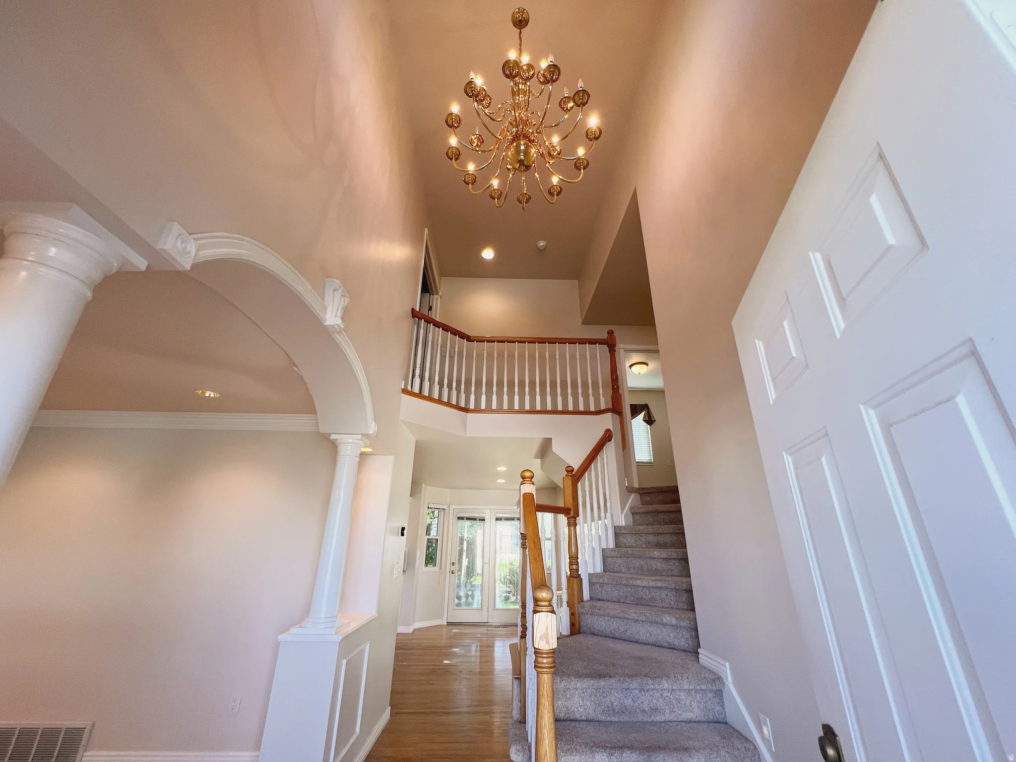 Two-story foyer featuring a brass chandelier and a carpeted staircase with wood-finish handrails