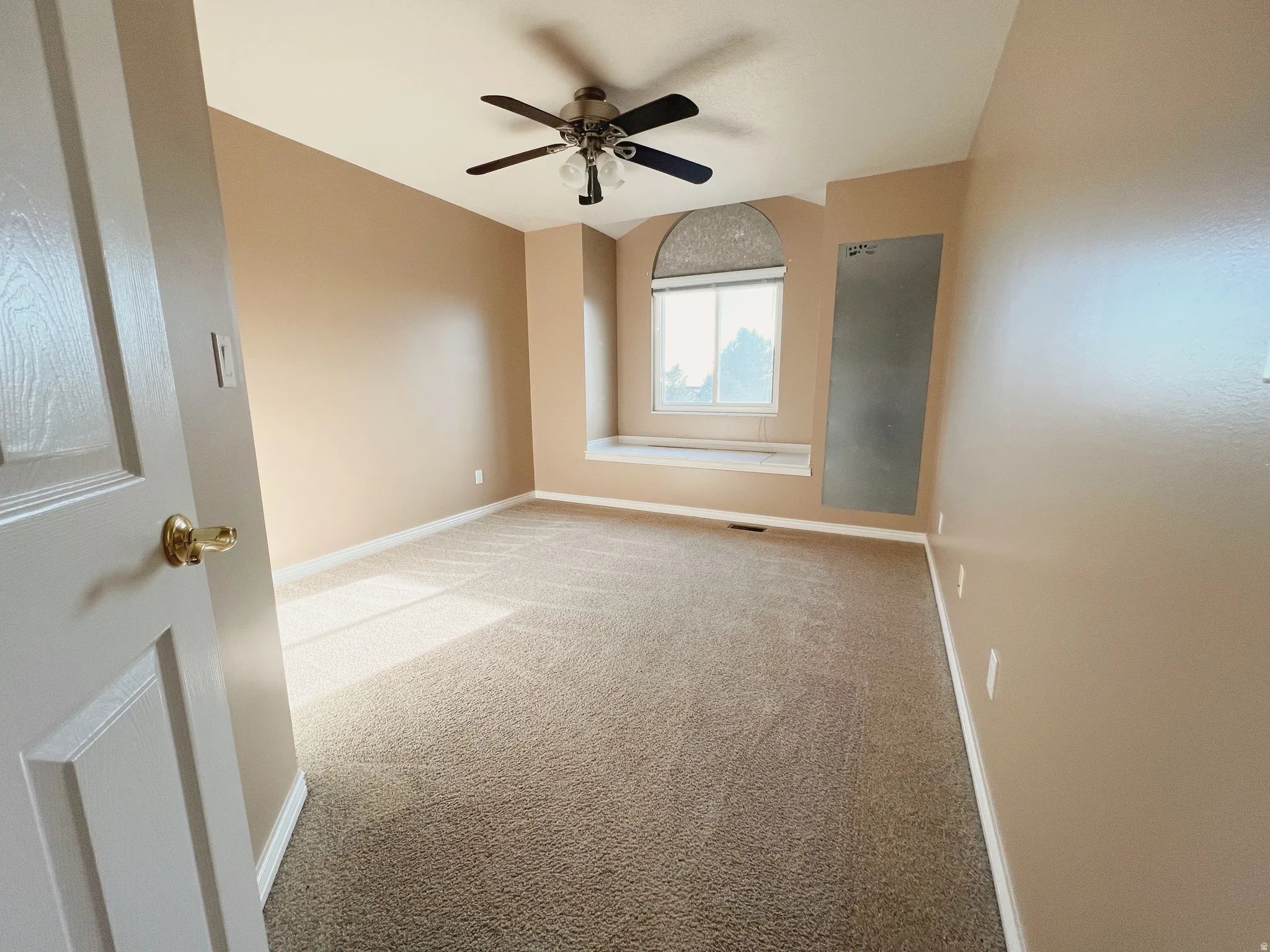 Neutral tone walls with white trim, brown patterned carpet, and a ceiling fan