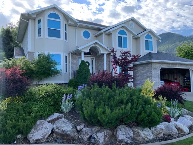 Contemporary stucco exterior with brick accents, featuring an arched entry and a two-car garage