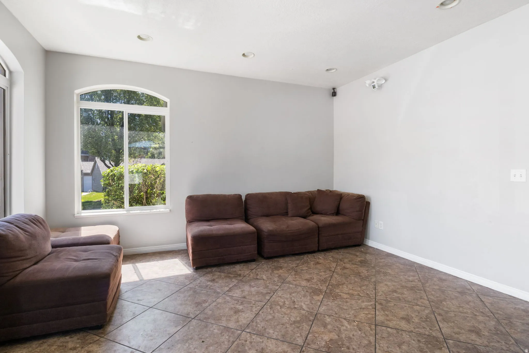 Spacious room featuring light gray walls, recessed lighting, and tile flooring