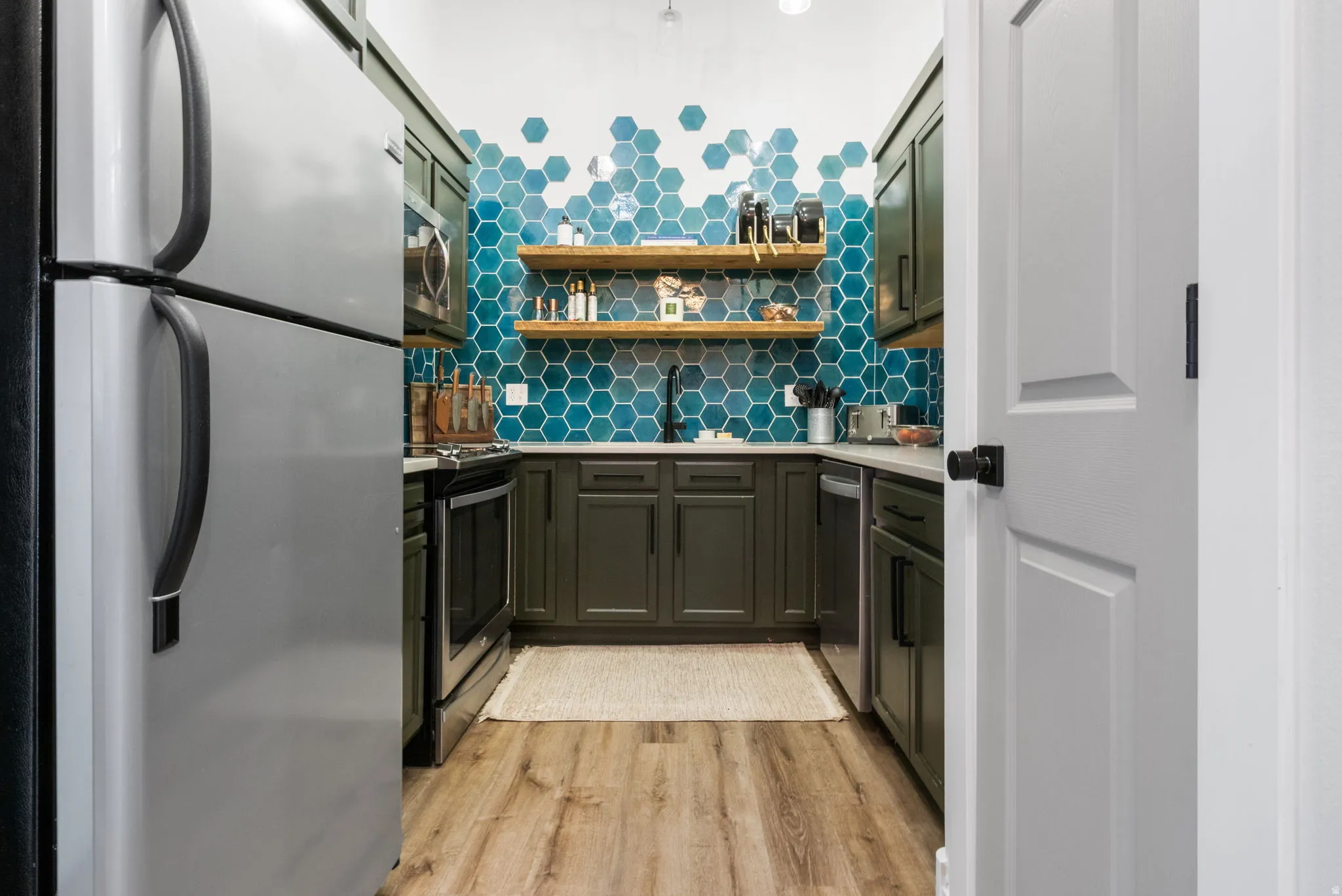 Galley kitchen featuring wood-finish flooring, dark cabinetry, and light countertops