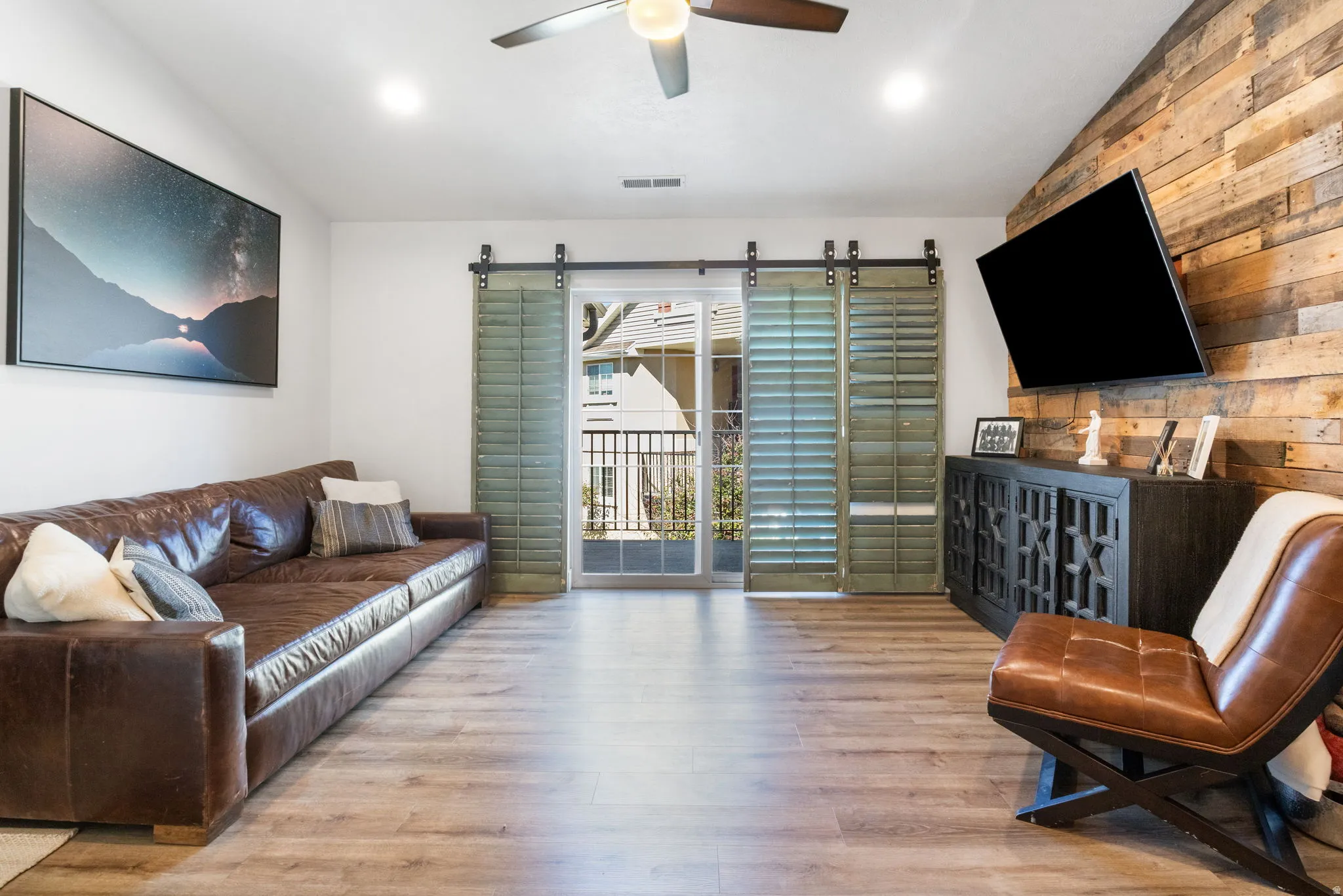 Living area featuring wood-finish flooring, a wood plank accent wall, and sliding glass doors to a balcony