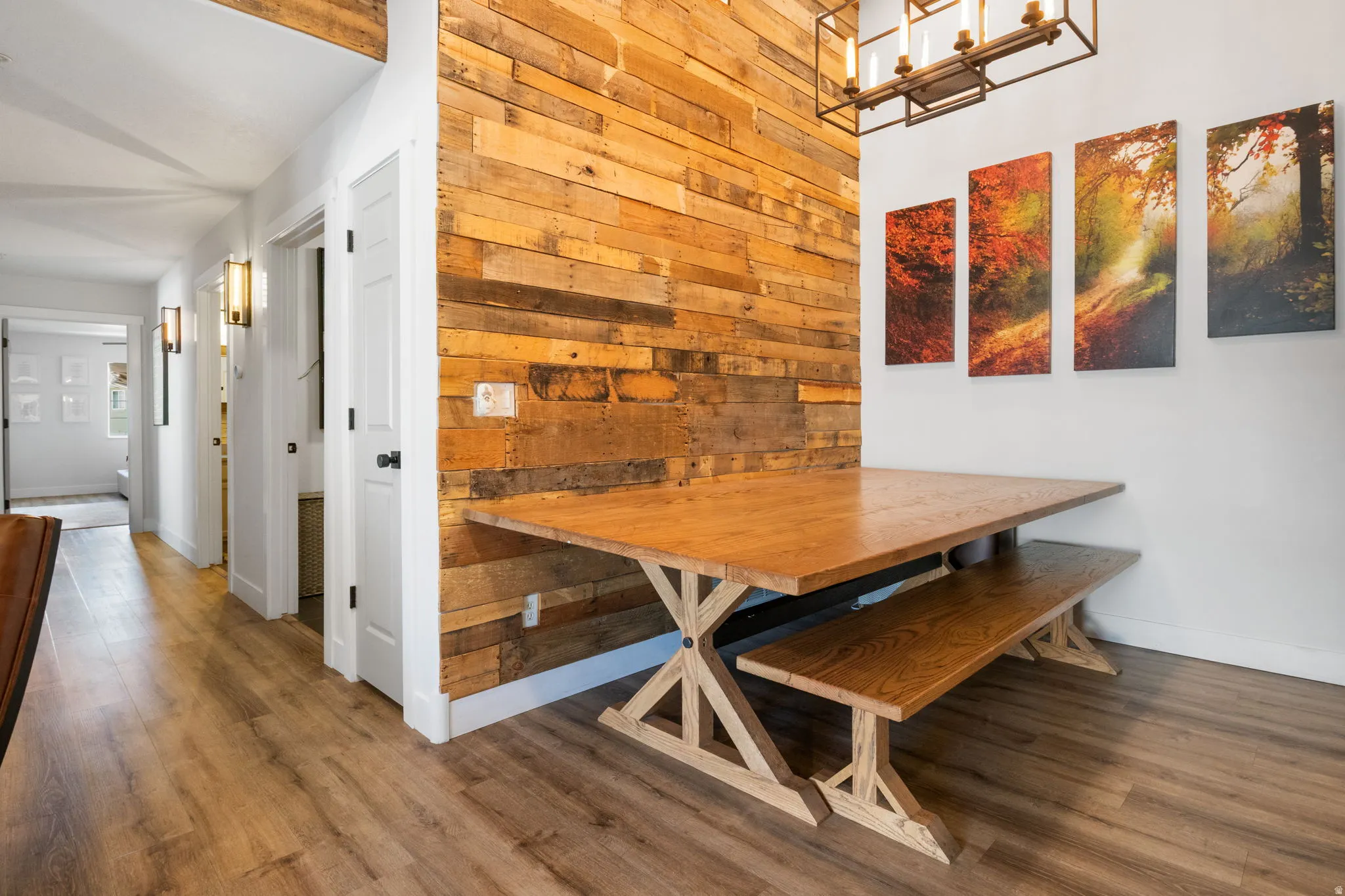 Dining area featuring a wood plank accent wall, wood-finish flooring, and a rectangular chandelier