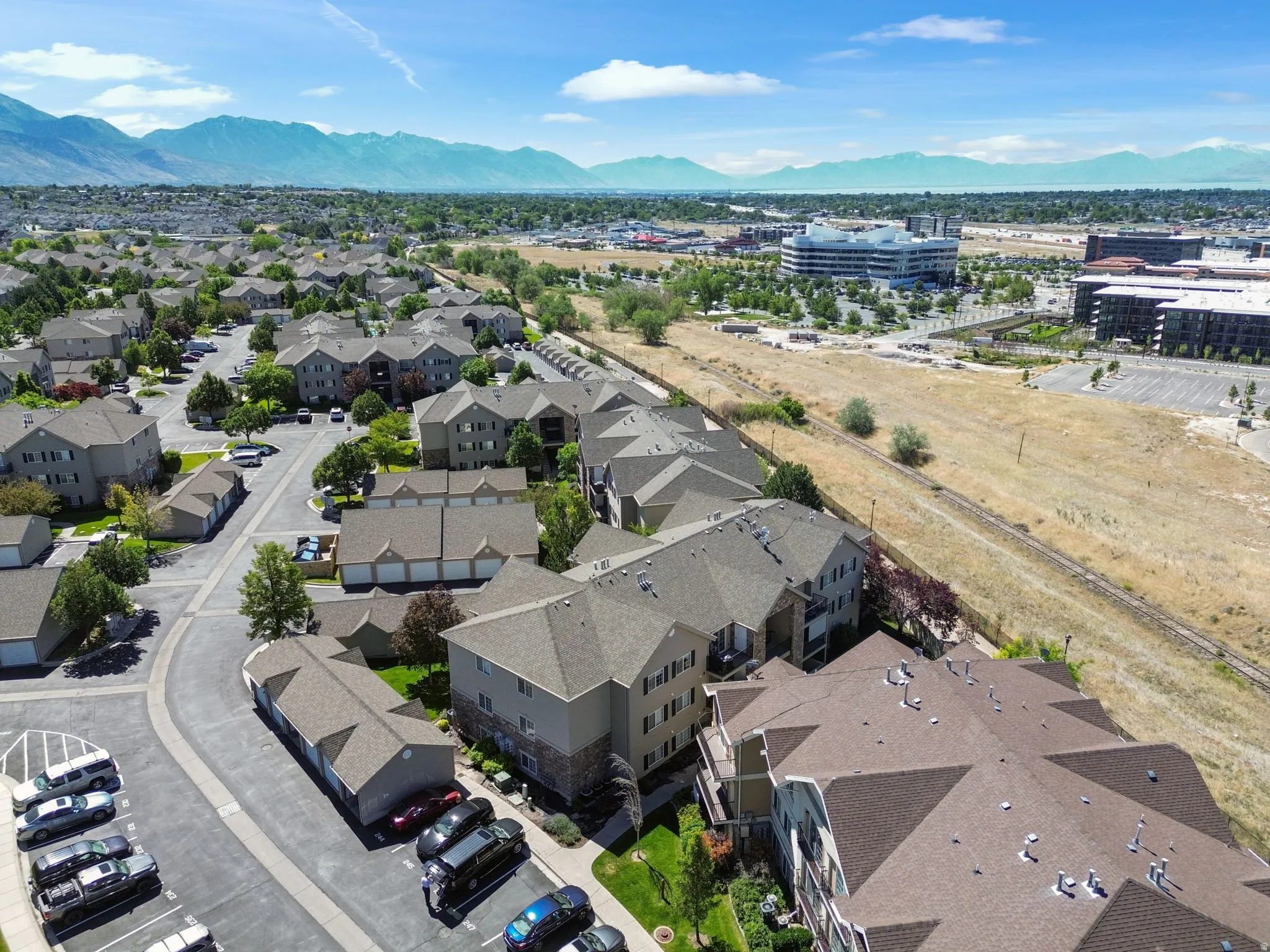 Aerial perspective of a multi-building residential community featuring pitched shingle roofs and integrated parking areas
