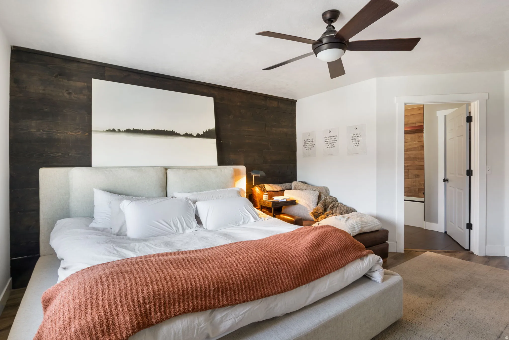 Bedroom featuring a dark wood-paneled accent wall, a ceiling fan with integrated lighting, and a neutral-toned area rug