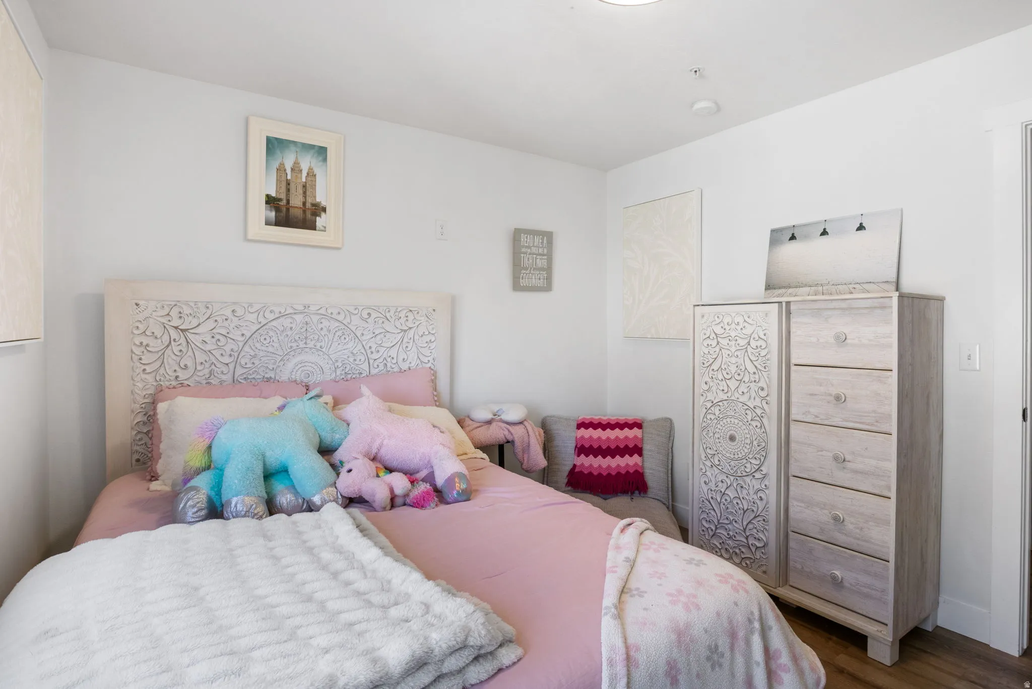 Bright bedroom featuring light-toned wood-finish flooring and white walls