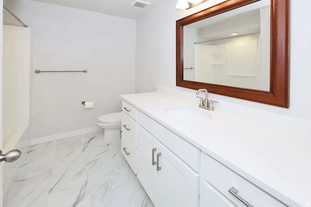 Bathroom featuring a white vanity with integrated sink, brushed nickel faucet, and a large framed mirror