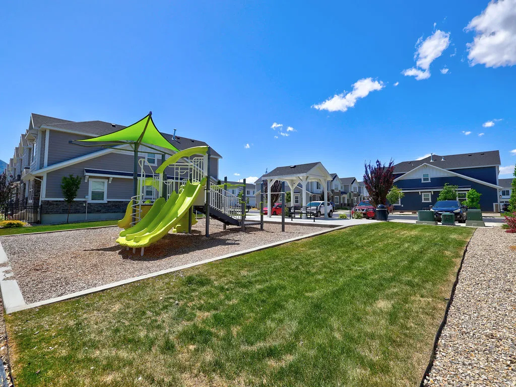 Recreational area featuring a playground structure with multiple slides and a shade canopy