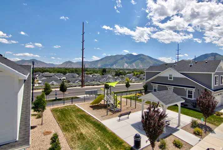 Community green space featuring a shaded pergola, playground structure, and landscaped shrubbery