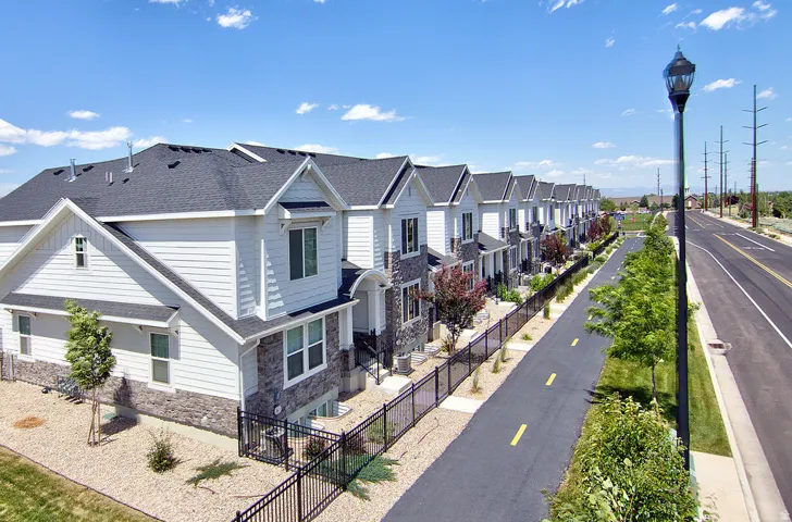 Modern townhome exterior featuring white siding, stone accents, and dark pitched roofing