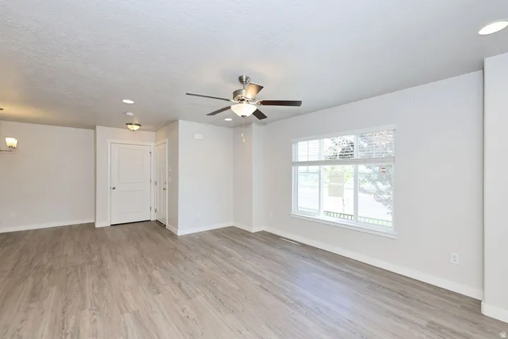 Bright interior featuring wood-finish flooring, white walls, and a large window with white blinds