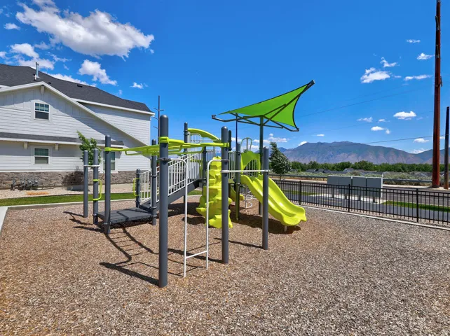 Modern playground structure featuring multiple slides, climbing elements, and a green shade canopy