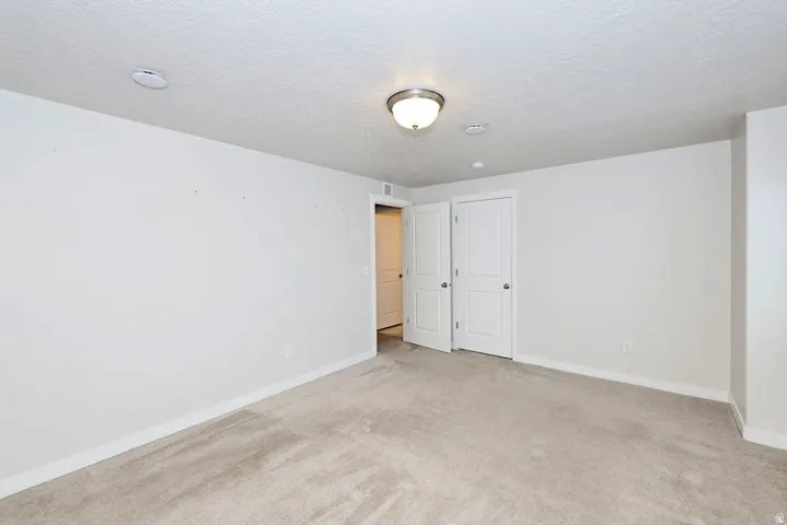 Carpeted room featuring white walls and baseboards