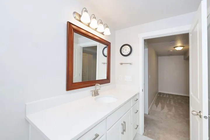 Bathroom vanity featuring a white countertop with an undermount sink, brushed nickel faucet, and a large mirror with a wood-finish frame