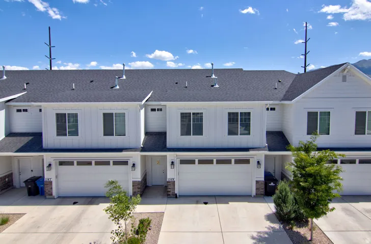 Modern townhome exterior with white vertical siding and dark shingle roofing