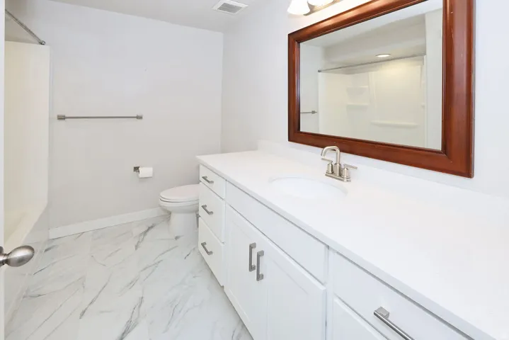 Bathroom featuring a white vanity with integrated sink, brushed nickel faucet, and a large framed mirror