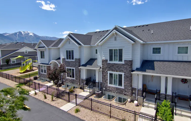 Townhome exterior featuring gray stone veneer and white siding