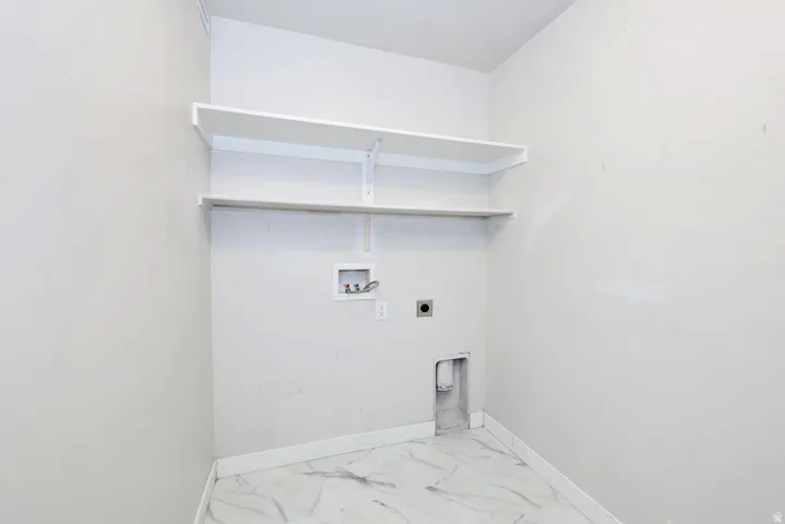 Utility room with white walls, two white shelving units, and marble-finish tile flooring