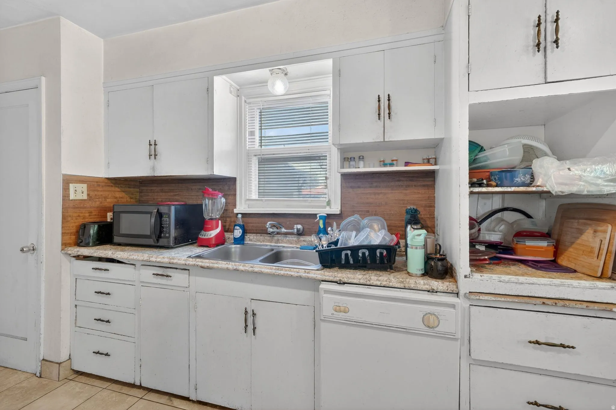 Kitchen featuring wood-finish backsplash, white cabinetry with bronze hardware, and a stainless steel double basin sink
