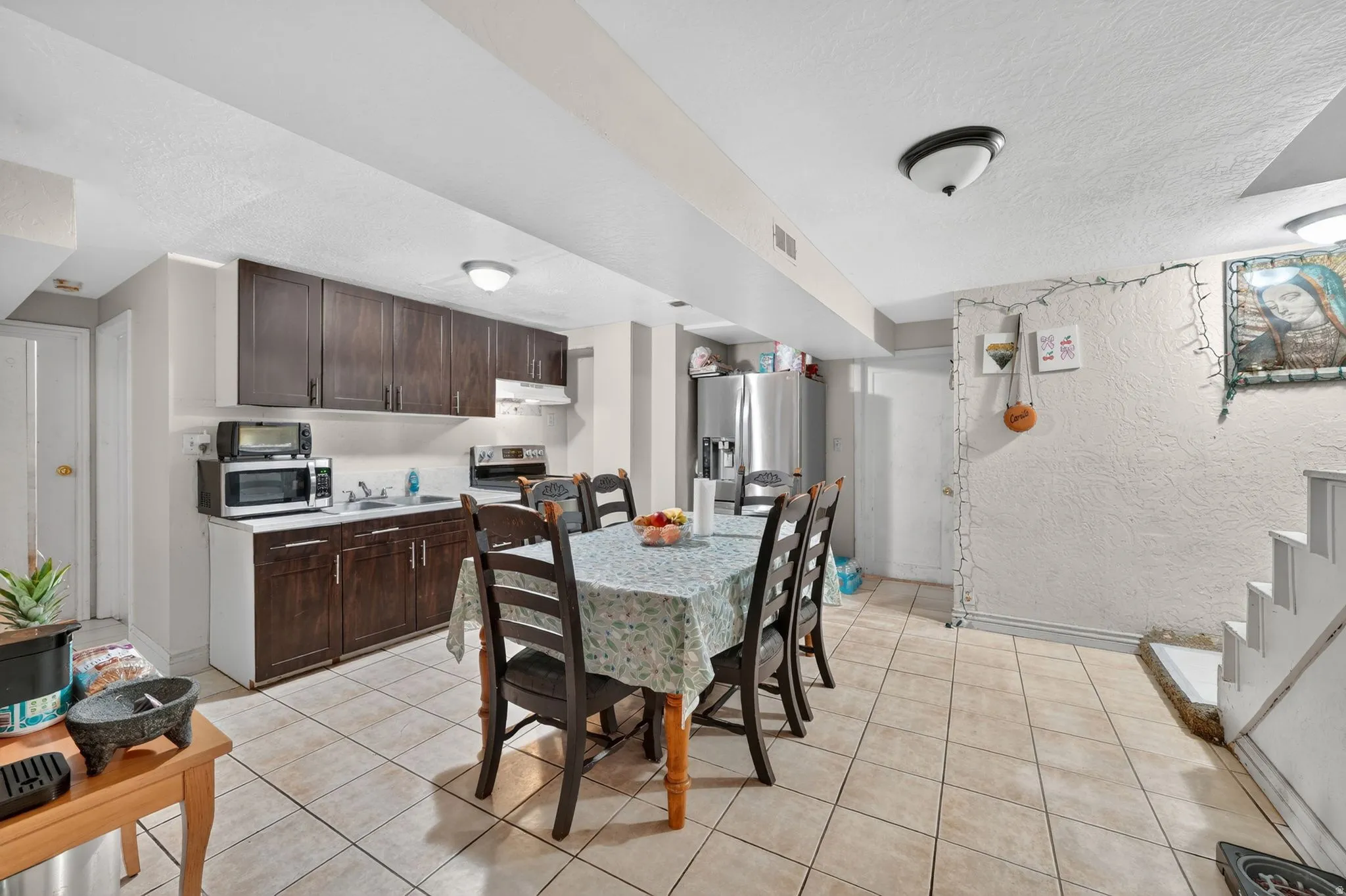 Open-concept kitchen and dining area featuring dark wood-finish cabinetry, a stainless steel refrigerator, and tiled flooring